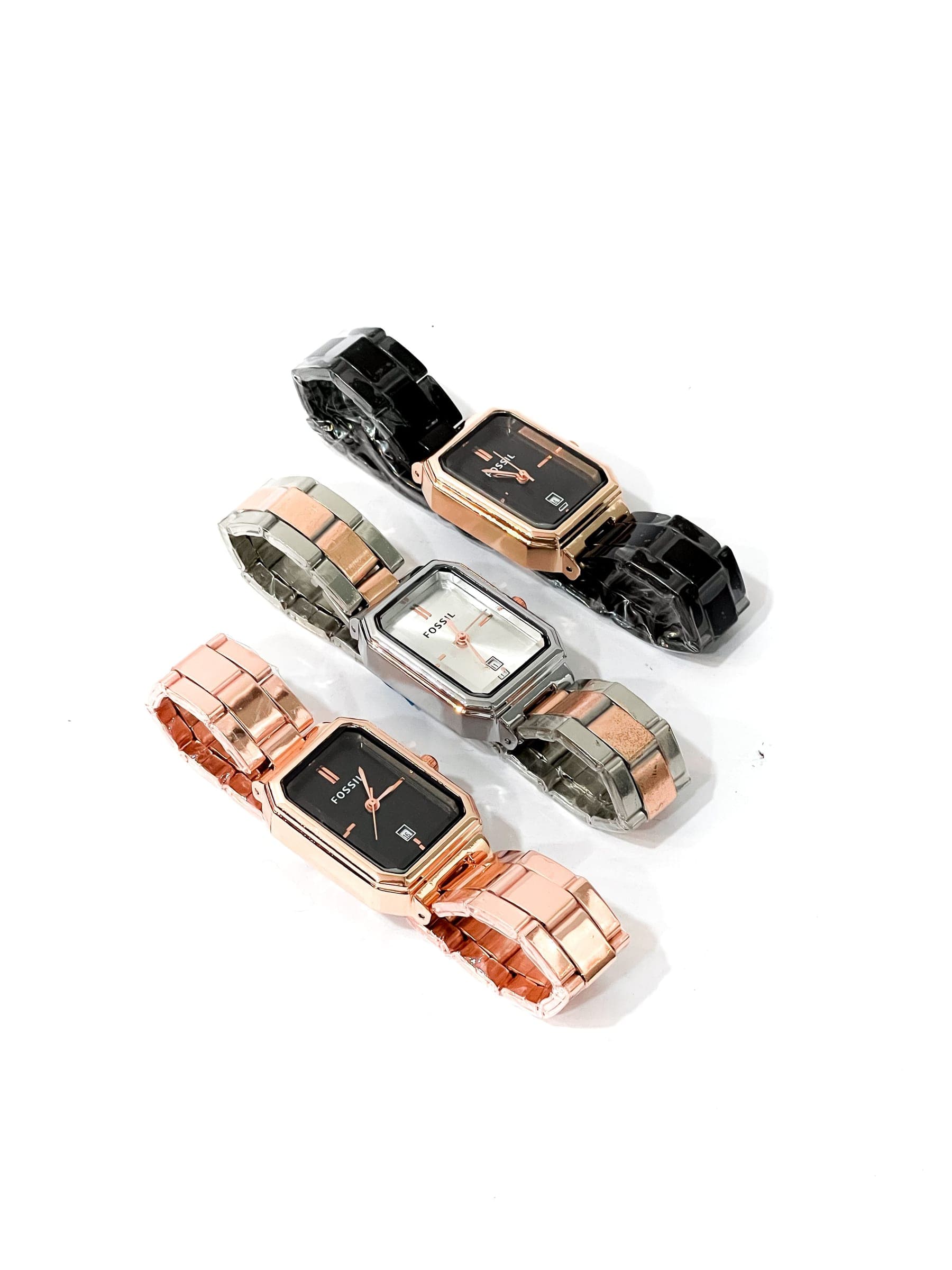 Trois montres à boîtier rectangulaire sur fond blanc, à bracelets noir, argenté et or rose.